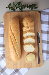 Photo of Whole and cut baguettes with fresh butter on table, flat lay