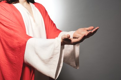 Photo of Jesus Christ reaching out his hands on grey background, closeup
