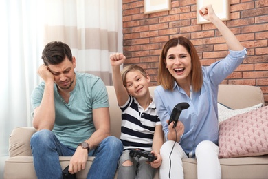 Photo of Happy family playing video games on sofa in living room
