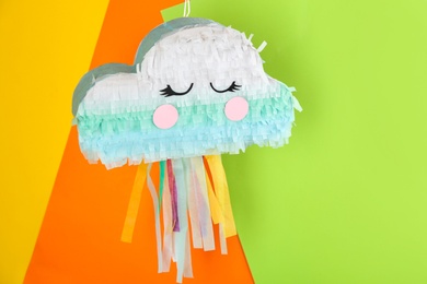 Photo of Cloud shaped pinata hanging on color background