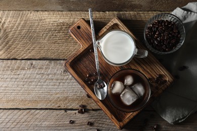 Photo of Delicious iced coffee, milk and beans on wooden table, flat lay. Space for text
