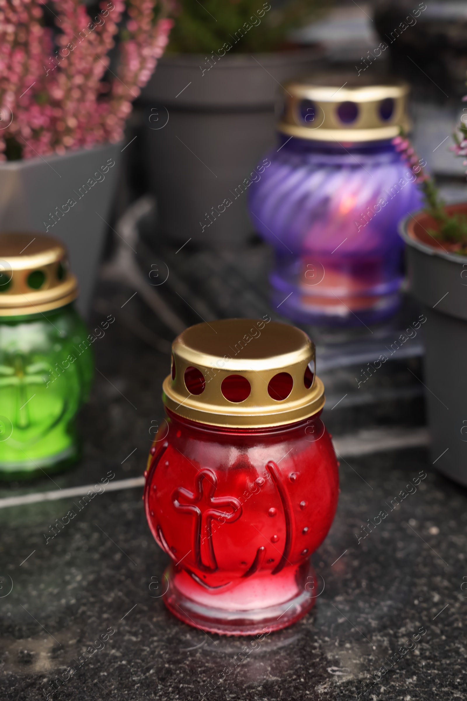 Photo of Different grave lanterns on granite surface at cemetery