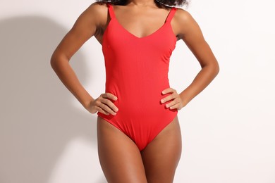 Photo of Woman in red one-piece summer swimsuit on white background, closeup