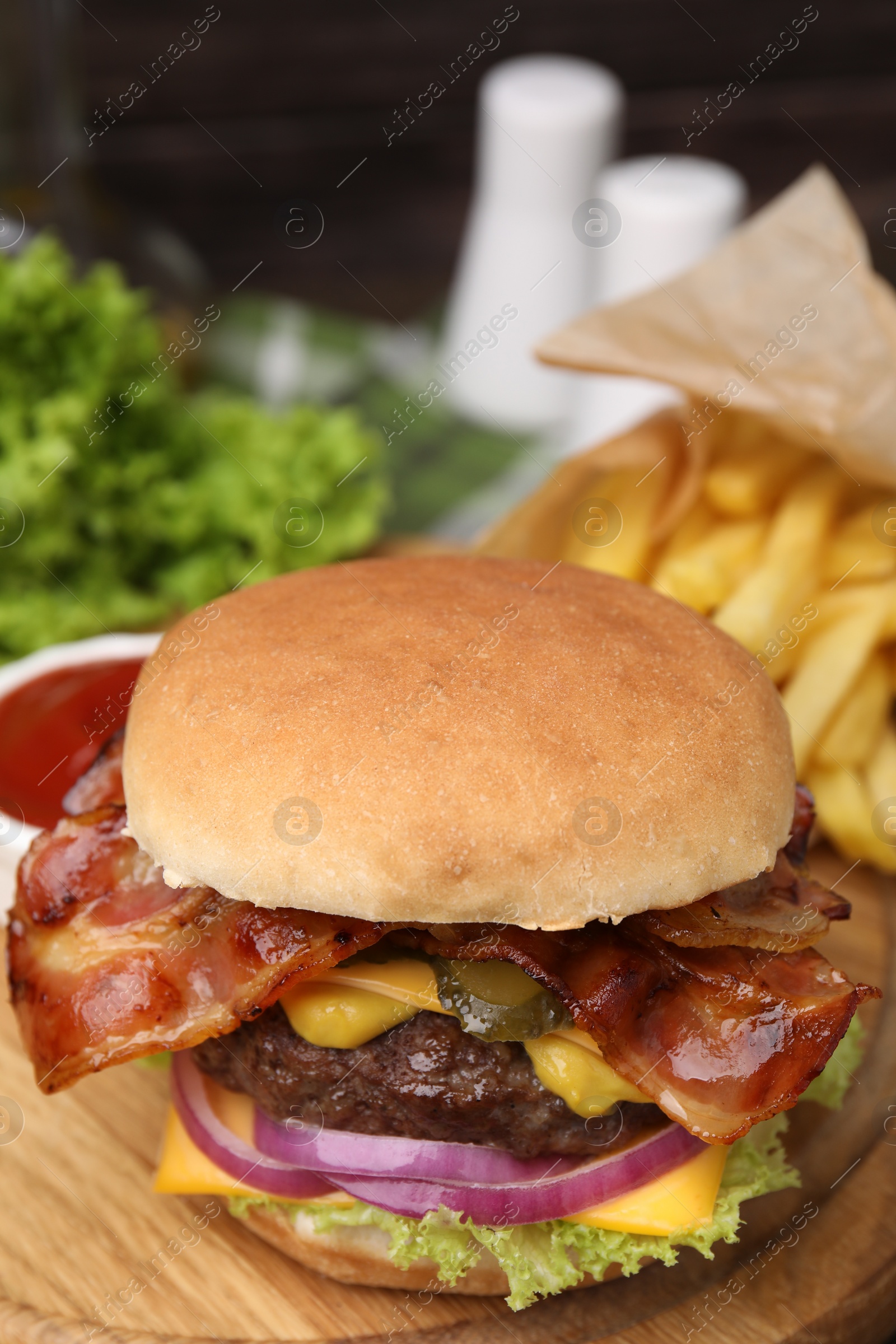 Photo of Tasty burger with bacon, vegetables and patty on wooden board, closeup