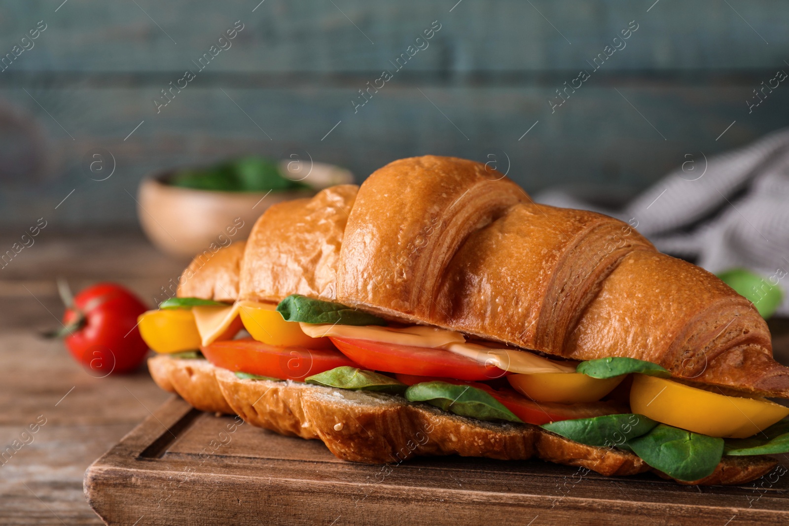 Photo of Tasty croissant sandwich on wooden table, closeup