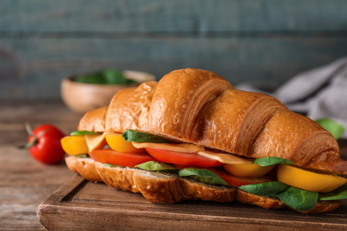 Tasty croissant sandwich on wooden table, closeup