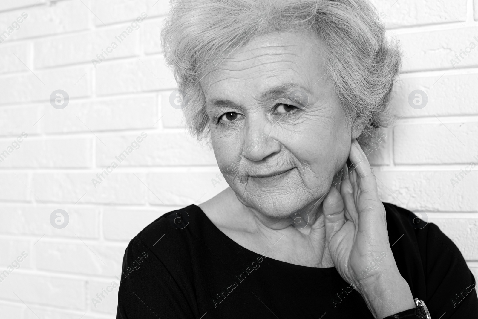 Image of Portrait of mature woman near brick wall. Black and white photography