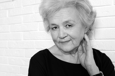 Image of Portrait of mature woman near brick wall. Black and white photography