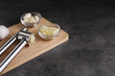 Photo of Garlic press, cloves and mince on grey table. Space for text