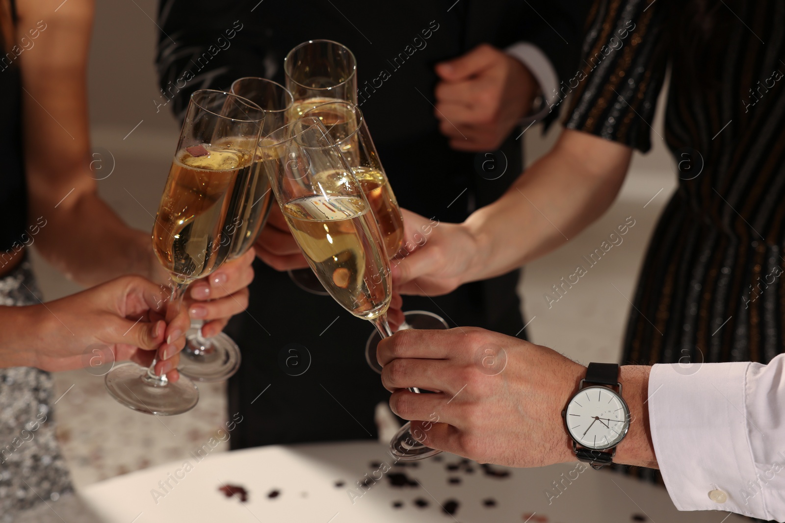 Photo of Friends clinking glasses of sparkling wine indoors, closeup. New Year celebration