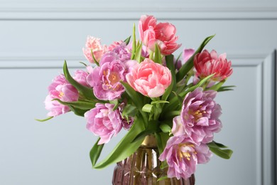 Photo of Beautiful bouquet of colorful tulip flowers near light grey wall, closeup