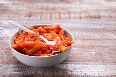 Photo of Bowl and spoon with delicious lecho on wooden table, closeup. Space for text