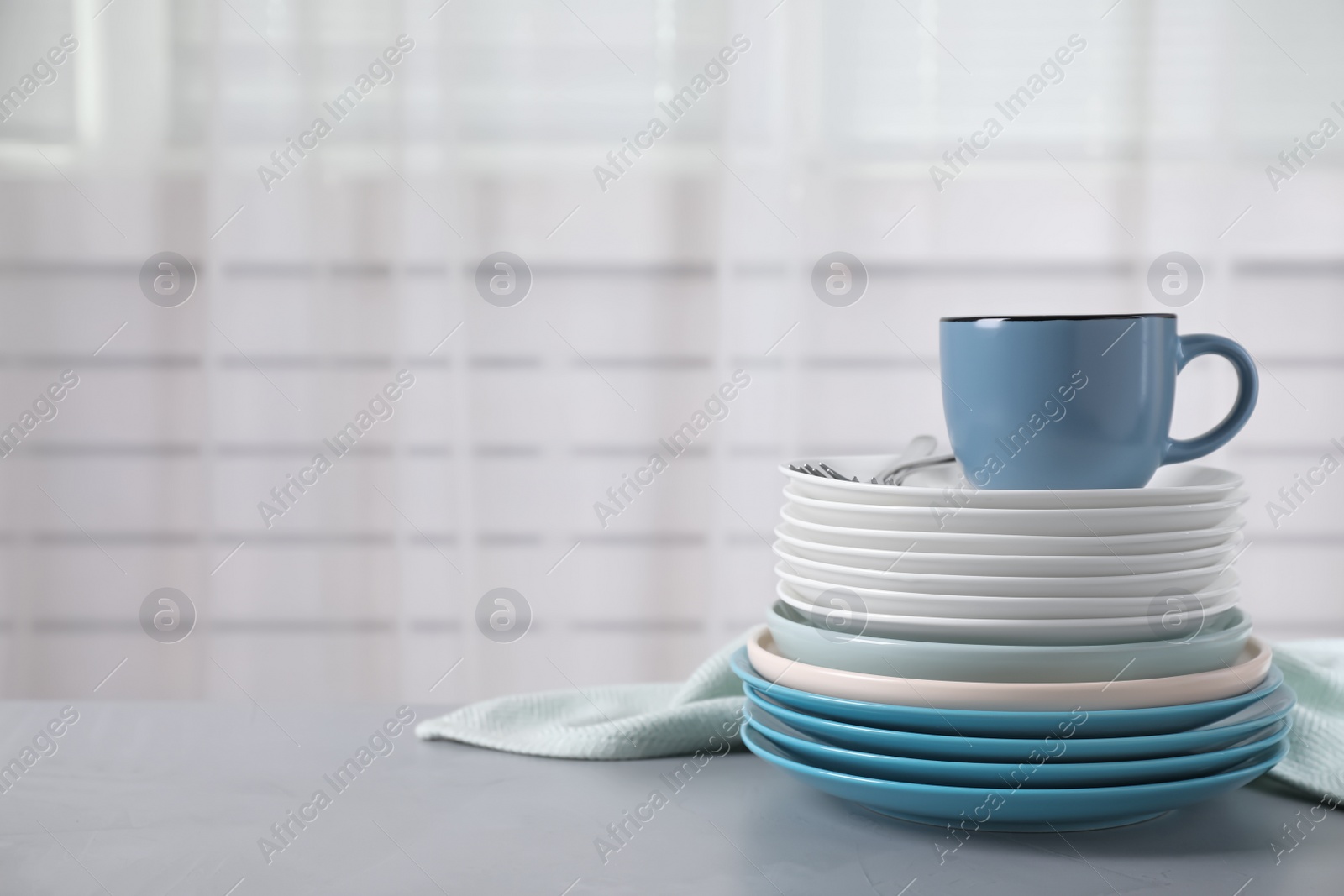 Photo of Set of clean tableware on light grey table. Space for text