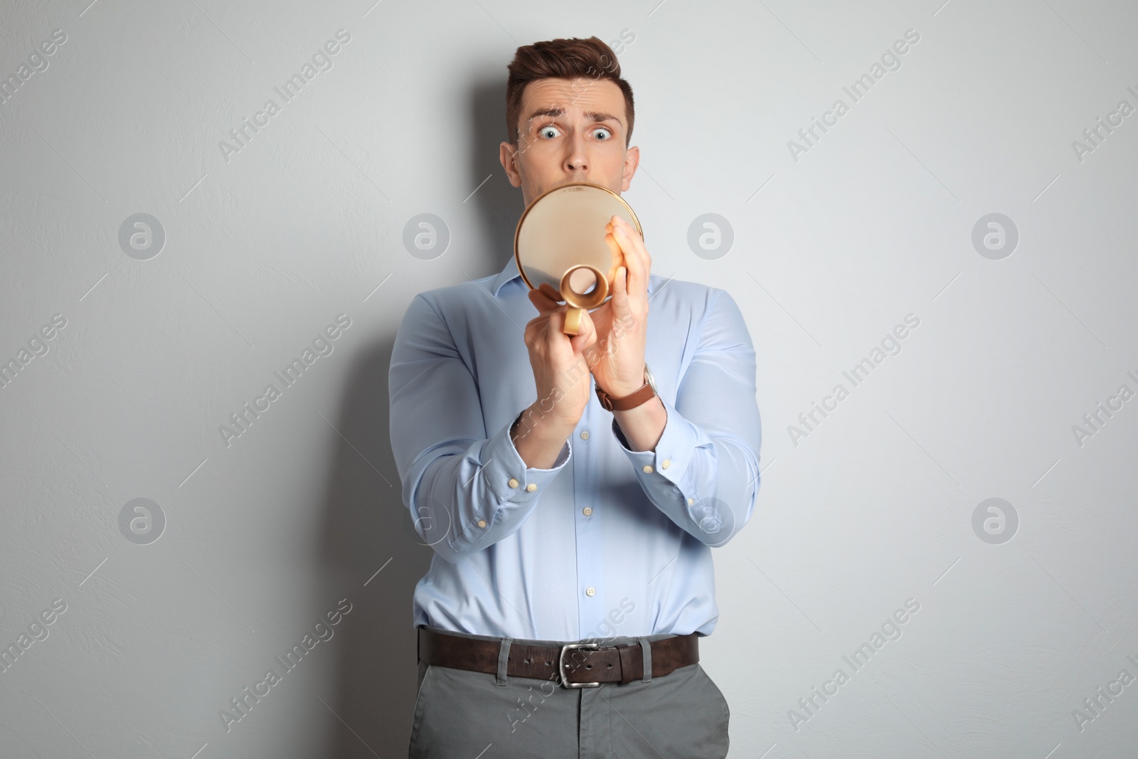 Photo of Young man with megaphone on light background