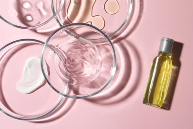 Photo of Many Petri dishes and cosmetic products on pink background, flat lay