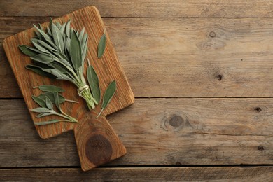 Board with fresh green sage on wooden table, top view. Space for text