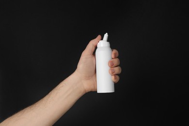 Photo of Man holding nasal spray on black background, closeup
