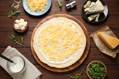 Photo of Flat lay composition with pizza crust and ingredients on wooden table