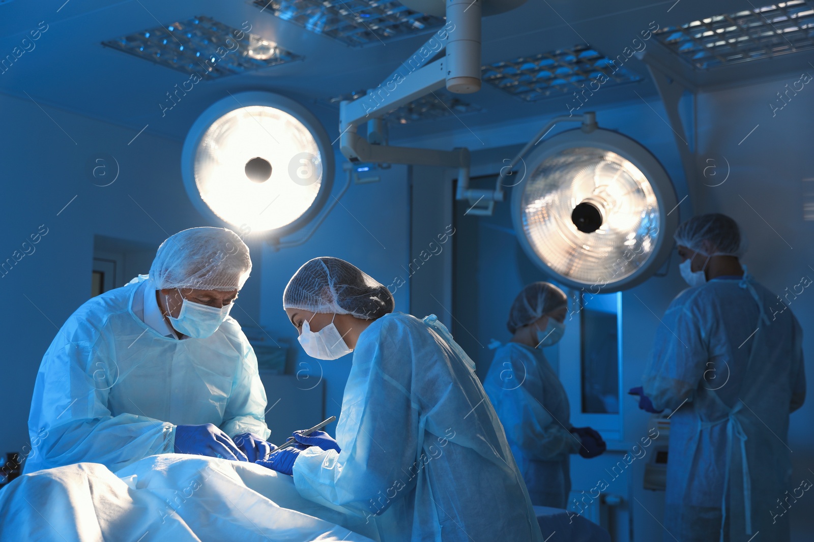 Photo of Team of professional doctors performing operation in surgery room