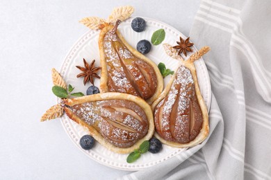 Photo of Delicious pears baked in puff pastry with powdered sugar on light table, top view