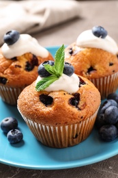 Photo of Plate of tasty muffins and blueberries on table, closeup