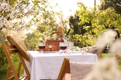 Photo of Stylish table setting with beautiful spring flowers, wine and croissants in garden