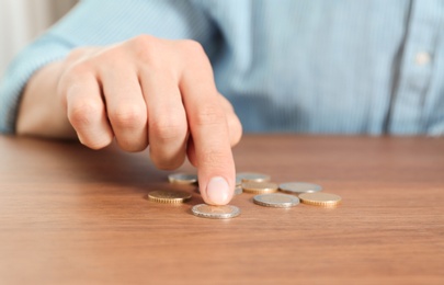 Photo of Man counting coins at table, focus on hand