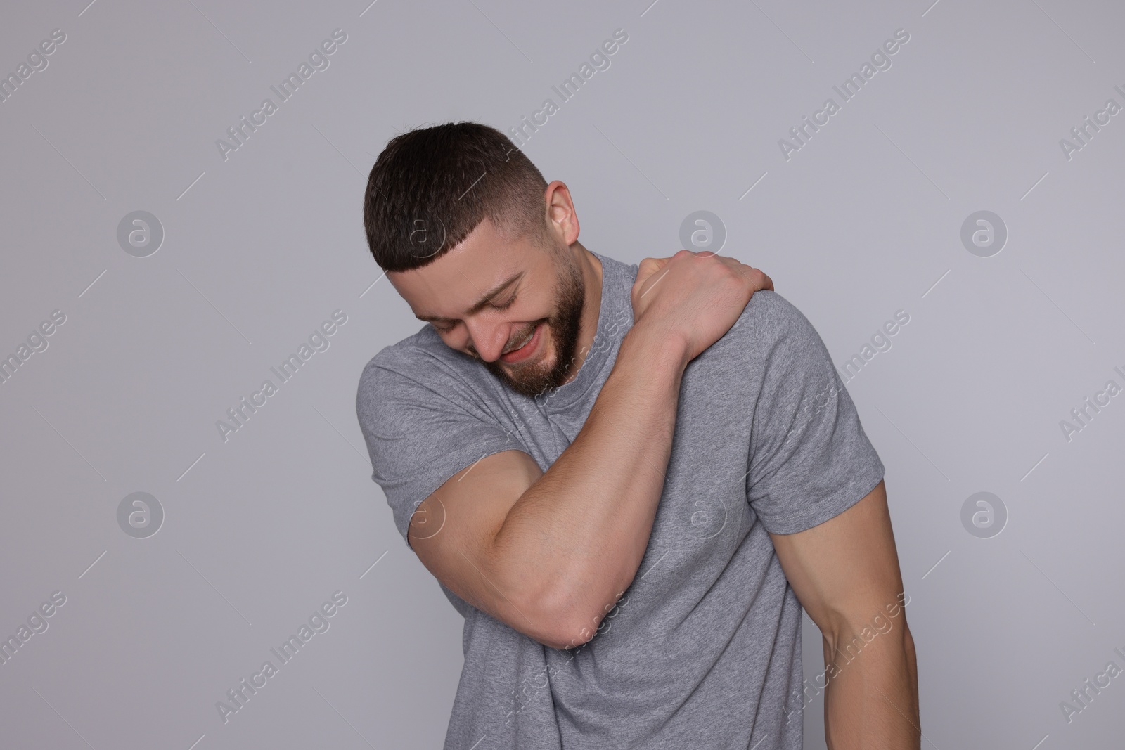 Photo of Man suffering from pain in his shoulder on light grey background. Arthritis symptom