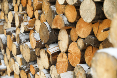 Photo of Stacked firewood with snow as background, closeup. Heating house in winter