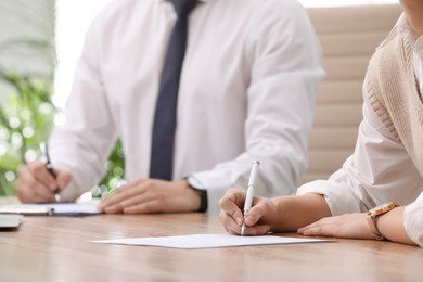 Photo of Woman signing contract at table in office, closeup.