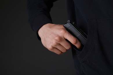 Photo of Man hiding gun in pocket against dark background, closeup