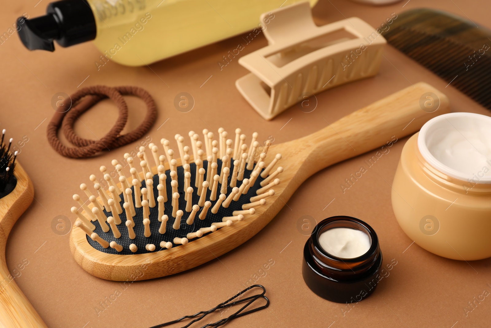 Photo of Wooden hairbrush, comb and different cosmetic products on light brown background