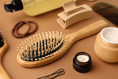 Photo of Wooden hairbrush, comb and different cosmetic products on light brown background