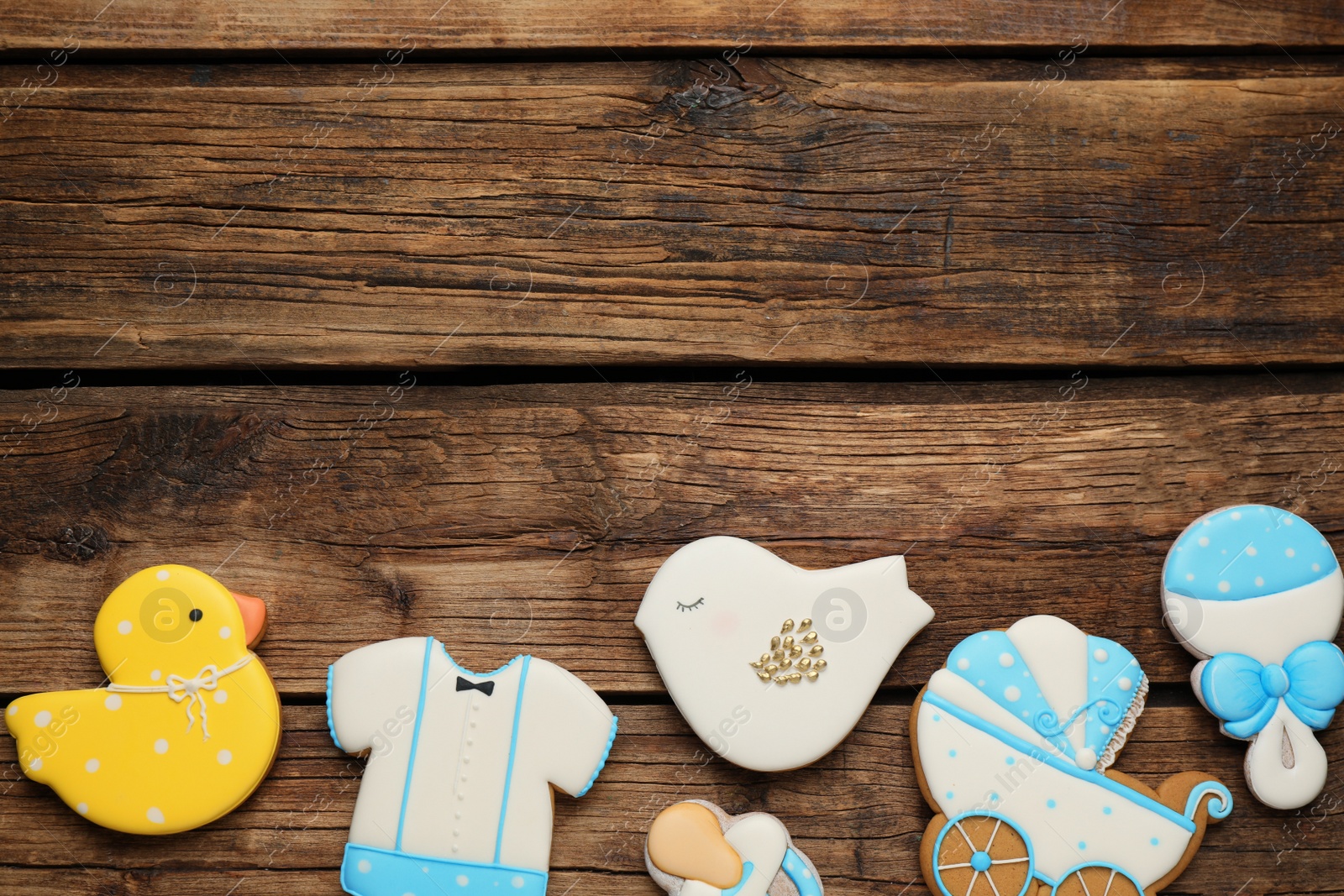 Photo of Cute tasty cookies of different shapes and space for text on wooden table, flat lay. Baby shower party