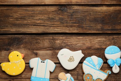 Cute tasty cookies of different shapes and space for text on wooden table, flat lay. Baby shower party