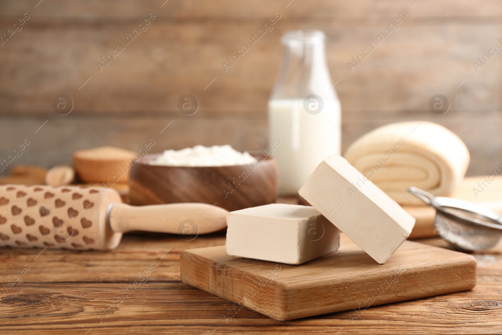 Photo of Blocks of compressed yeast and dough ingredients on wooden table, space for text