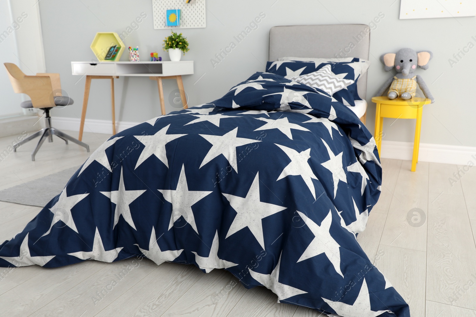 Photo of Bed with star patterned linens in child's bedroom. Interior design