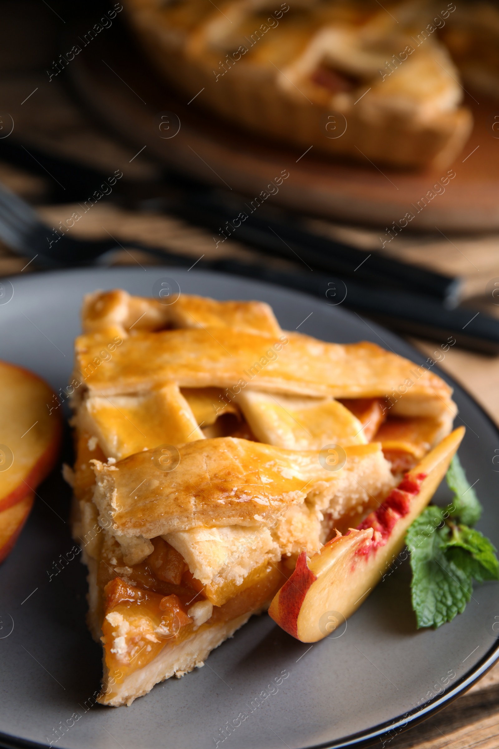 Photo of Piece of delicious fresh peach pie served on table, closeup