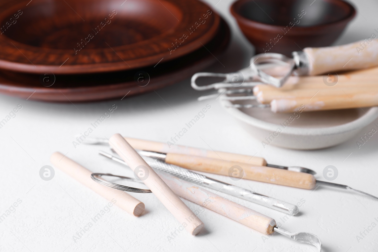 Photo of Set of different clay crafting tools on white table