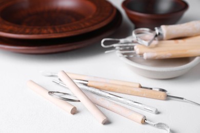 Set of different clay crafting tools on white table