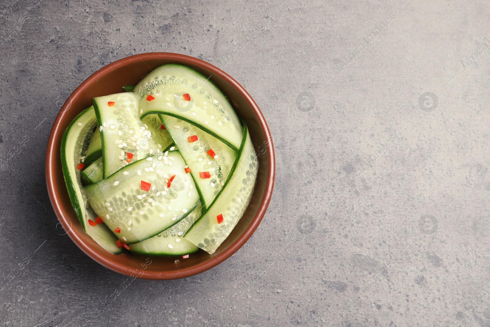 Photo of Dish with fresh cucumber salad on table, top view. Space for text