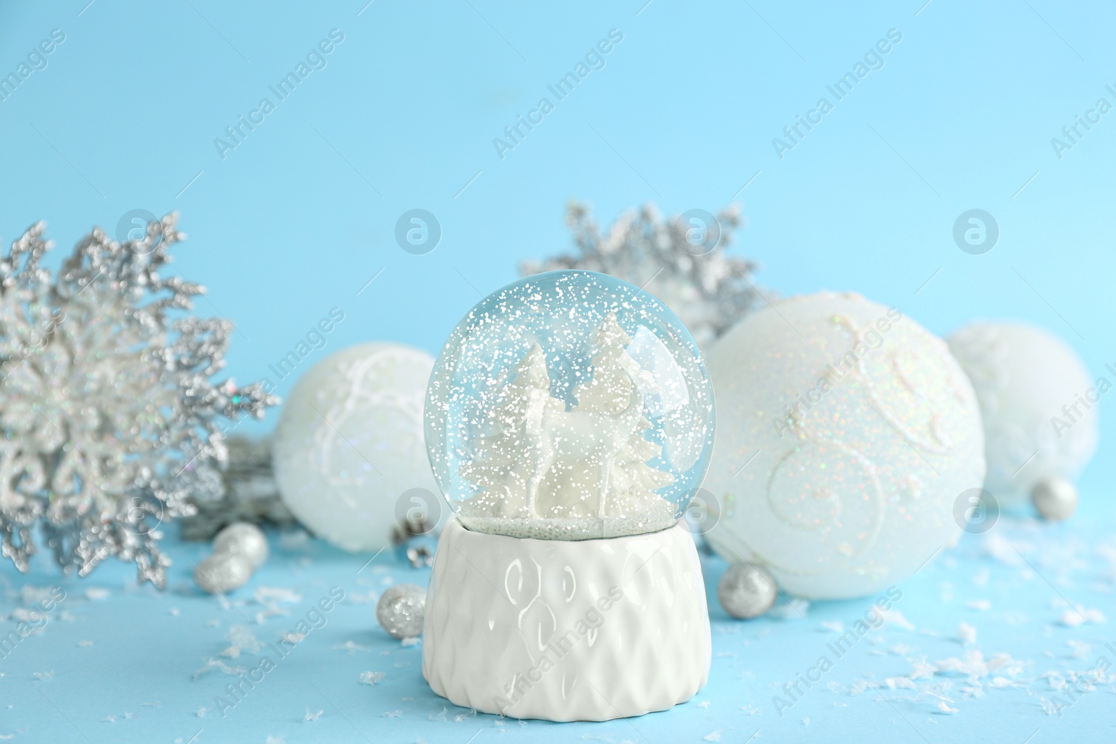 Photo of Beautiful Christmas snow globe and festive decor on light blue background