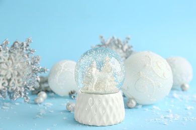 Photo of Beautiful Christmas snow globe and festive decor on light blue background
