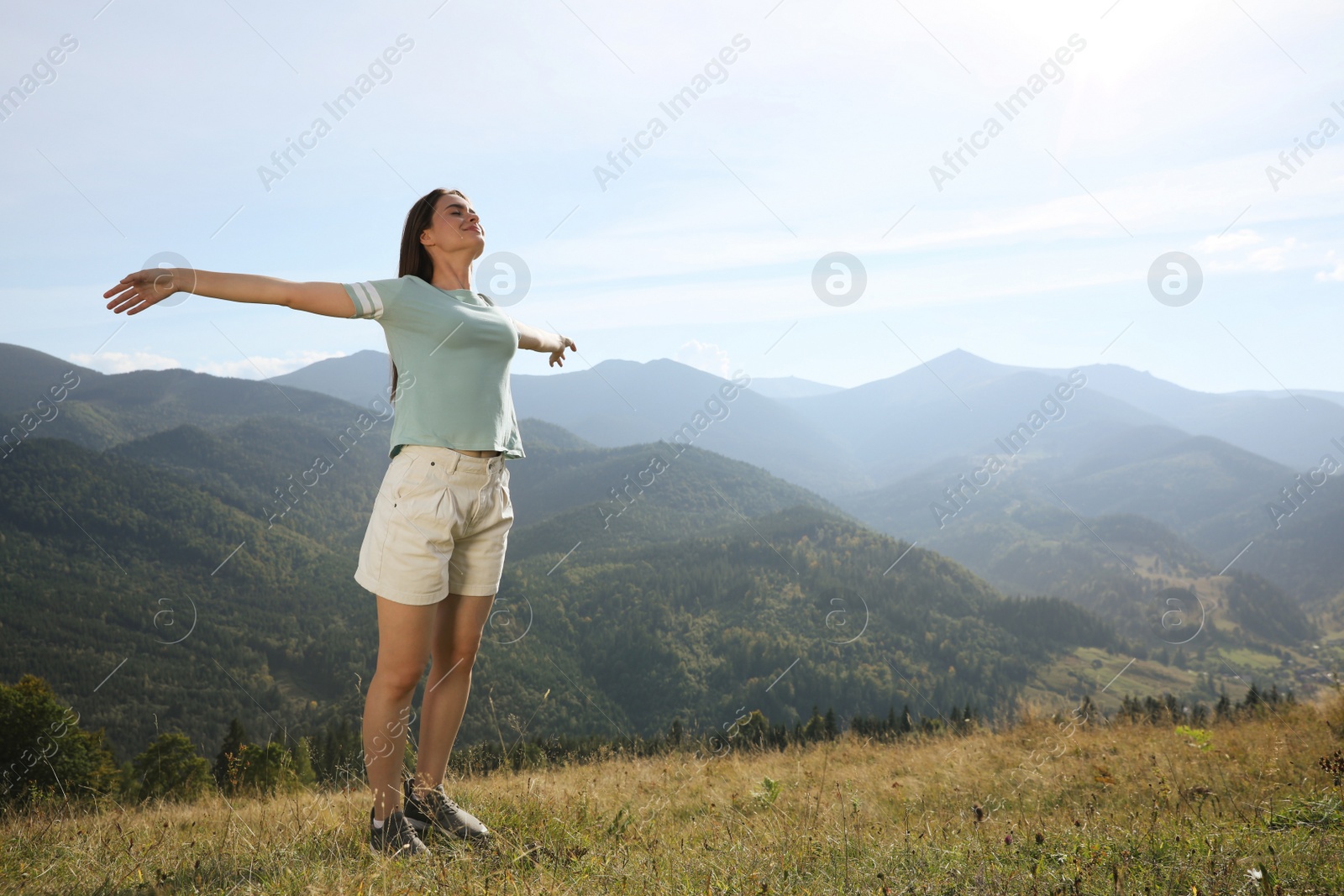 Photo of Beautiful young woman in peaceful mountains on sunny day. Feeling freedom