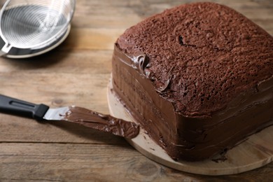 Delicious homemade layer cake with chocolate cream on wooden table, closeup