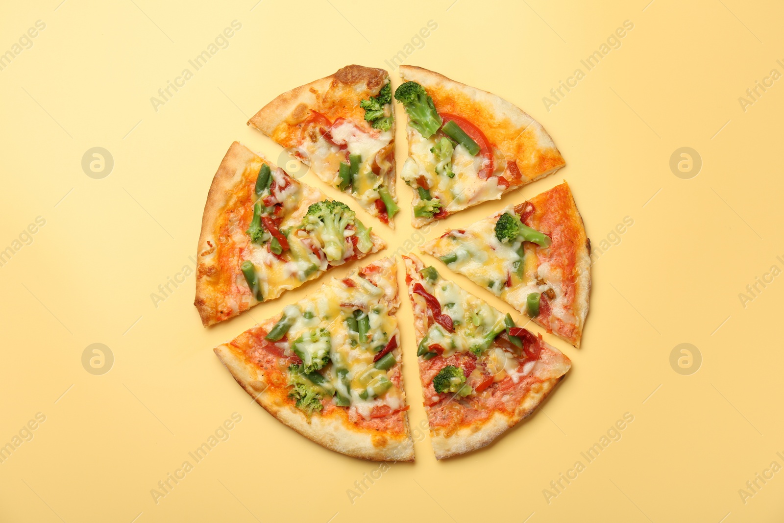 Photo of Delicious vegetarian pizza on yellow table, top view