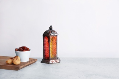 Photo of Muslim lantern Fanous and dried fruits on table against light background. Space for text