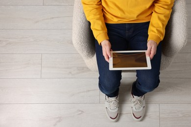 Photo of Man working with tablet in armchair, top view. Space for text