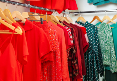 Photo of Different styling clothes on wooden hangers in wardrobe. Fashion blogger