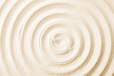 Photo of Zen garden pattern on sand as background, top view. Meditation and harmony